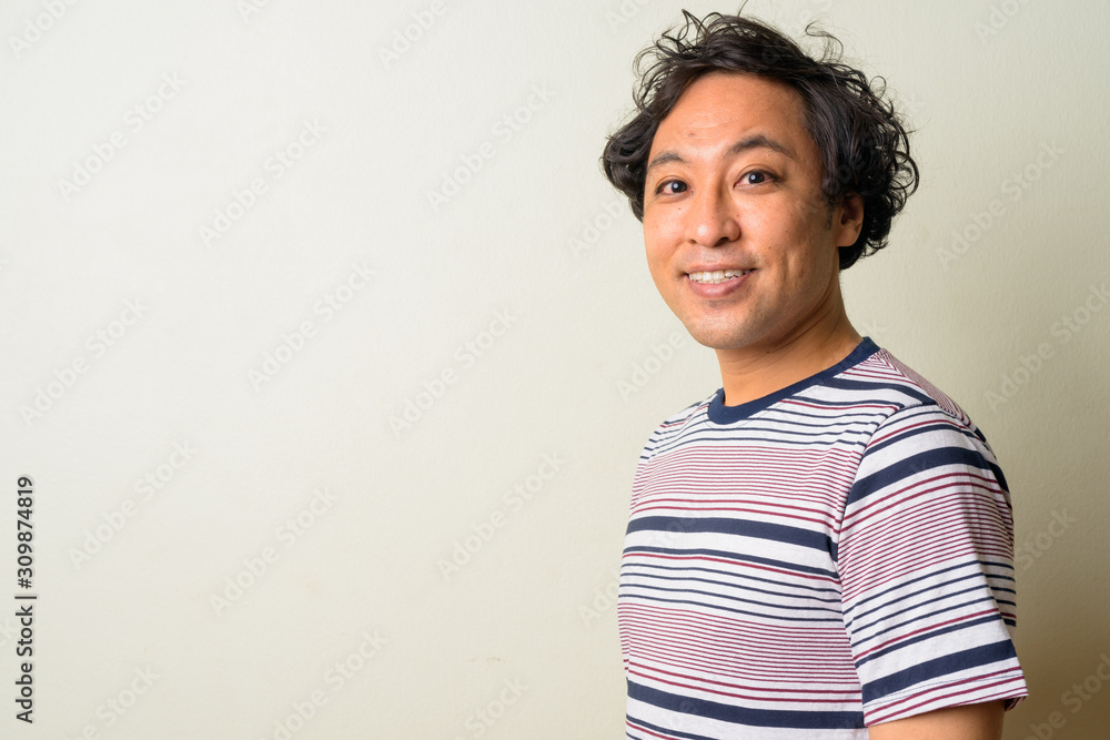 Profile view of happy Japanese man with curly hair smiling Profile view of happy Japanese man with curly hair smiling