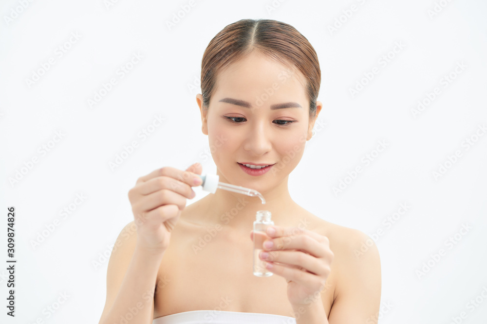 Young Asian girl applying serum or skin care product on her face. Isolated on white background. Young Asian girl applying serum or skin care product on her face. Isolated on white background.