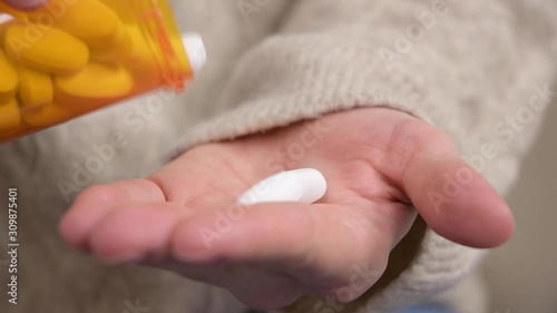 Woman pours two pills into the palm of her hand and takes antibiotic tablets