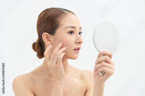 Shot of a beautiful young woman looking at herself in small mirror over white isolated background.