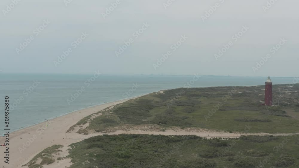 Cinematic drone / aerial circling panorama shot of a brick lighthouse with grass / meadow in the foreground and the north sea at the background at a day, 25p Cinematic drone / aerial circling panorama shot of a brick lighthouse with grass / meadow in the foreground and the north sea at the background at a day, 25p