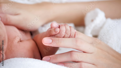 Cute newborn baby touching mother s hand.