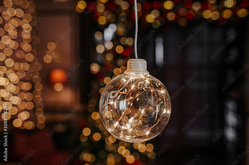 one large glass bulb with light from the garland inside, on a background of yellow and red bokeh from Christmas garlands and a Christmas tree one large glass bulb with light from the garland inside, on a background of yellow and red bokeh from Christmas garlands and a Christmas tree