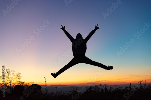 Silhouette of happy human jumping playing on mountain at sunset