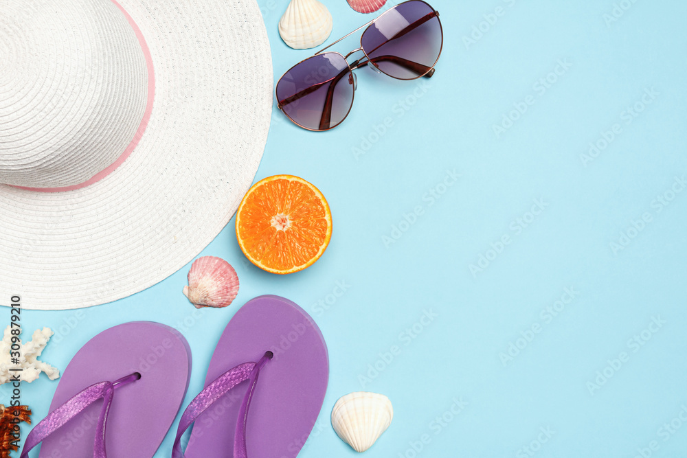Naklejka The concept of vacation sea summer travel. White hat glasses shells orange slippers on a blue background. Copy space, flat lay
