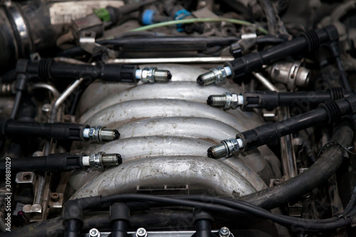 Spark plugs with high voltage wires on the engine under the hood of a car during diagnosis and repair in a workshop for vehicles. Auto service industrial.