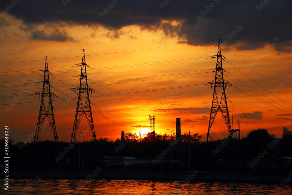 Big masts of an air power line in dusk, power grid on Golden evening Sunset background in Moscow - industrial landscape, enveronment,ecology, traditional energy, electric power transportation