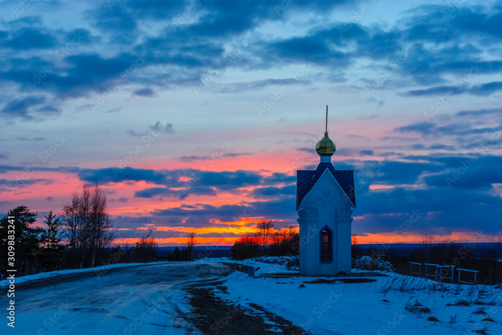 White country orthodox chapel and glimpses of a beautiful winter sunset