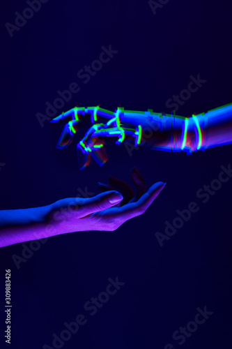 Woman and robot's hands as a symbol of connections between people and technology. Neon colors.