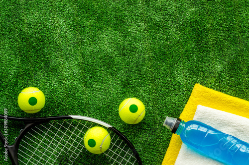 Tennis equipment - rockets, balls - on green grass background top-down frame copy space