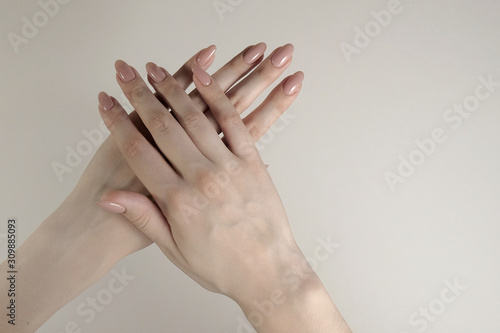 beautiful female hands with beige manicure on a white background