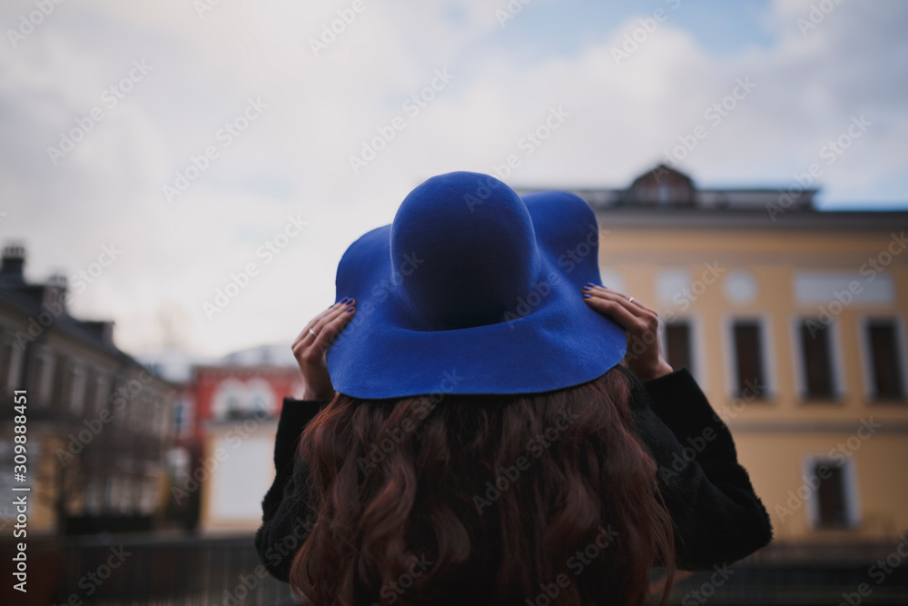 Young woman in a blue hat walks in the park.