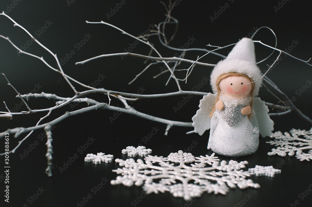 Obraz premium Black festive Christmas background with contrasting white objects - a natural painted white branch, snowflakes, Christmas toys and a white angel with wings, gifts in shiny silver packaging