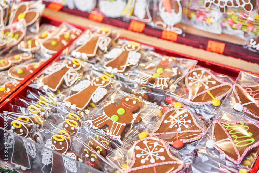 Fototapeta premium Ginger cookies of different shapes. Gingerbread man and christmas mood in blurred background. Christmas market in old town European small city.