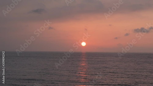 Red sunsets over sea video 4K. The sun touches horizon. Red sky, yellow sun and amazing sea. Summer sunset seascape. Atlantic Ocean beach sunsets. The sun in spindrift clouds Fantastic natural sunsets