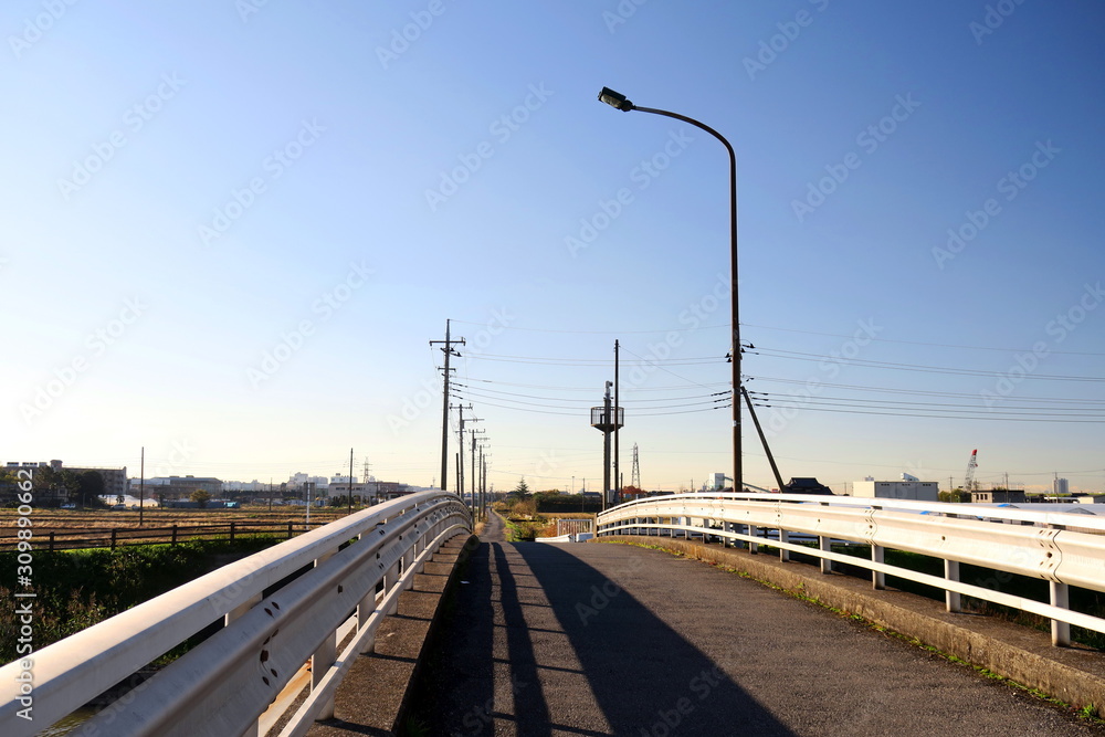 Obraz premium 冬空と農道に通じる橋風景