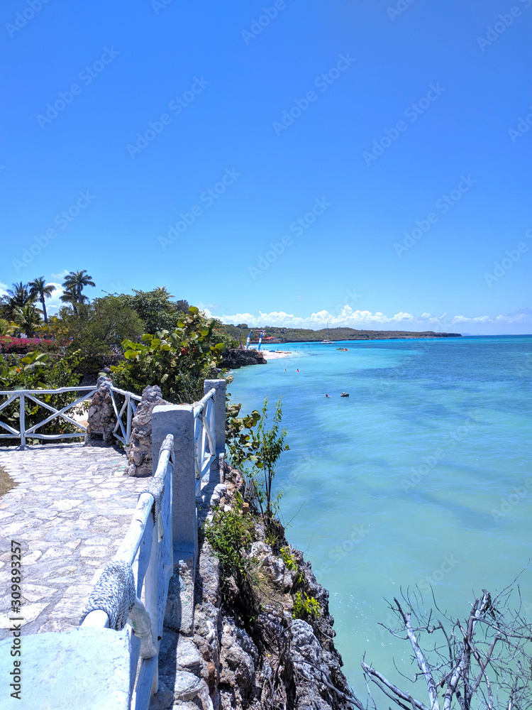 Fototapeta premium Wooden old fence on a paradise beach with a turquoise ocean against the blue sky of Cuba