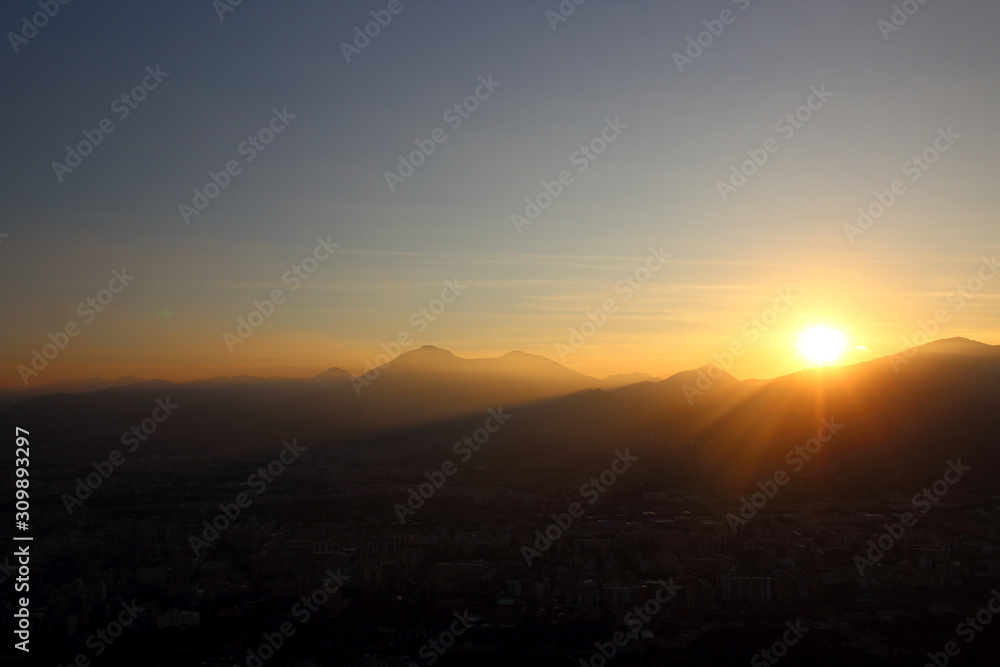 evocative image of sunset with silhouette of mountains in the background  and tree in the foreground
