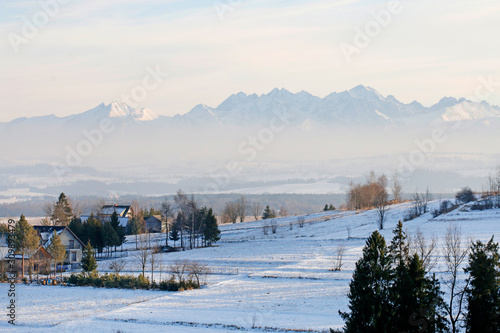 PIENIAZKOWICE, POLAND - DECEMBER 06, 2019: View of the village houses situated on the hills on a foggy winter morning. © agneskantaruk
