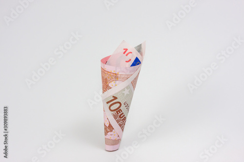 A ten euro banknote curled into cone shape uprignht on white background