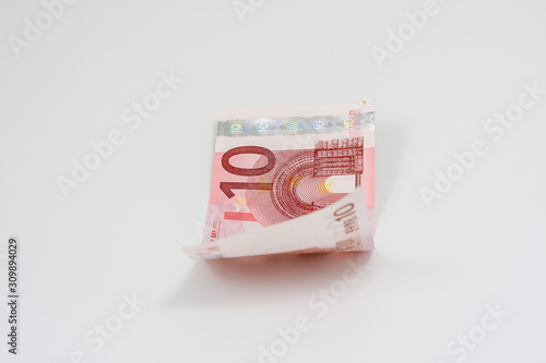 Slightly curled ten euro bill lies on white background