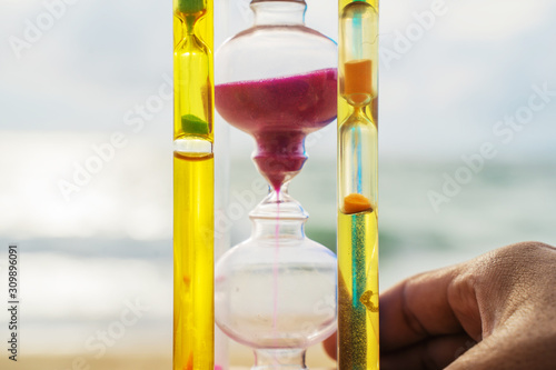 The hourglass passing time on the beach The hourglass in front of the bright blue sky with white clouds passing by Taking pictures in time lapse the concept of time, Phuket Thailand. photo