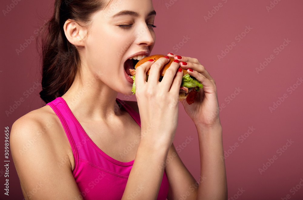 Studio portrait of hungry woman eating cheeseburger. Studio portrait of hungry woman eating cheeseburger.
