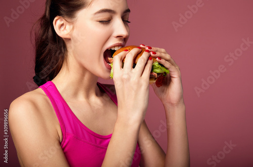 Studio portrait of hungry woman eating cheeseburger.