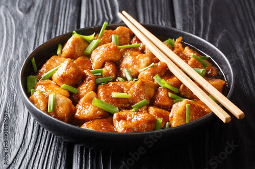 Fried chicken breast slices in sweet sauce with green onions close-up in a plate. horizontal