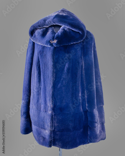 Short fur coat, avtoledi, bright blue with a hood, sleeves are decorated with longitudinal strips of fur. Vertical frame photo