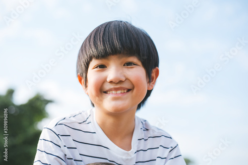 Happy cute Asian boy's smile on face portrait, relaxing at park in sunny day, family or successful parenting. - Image