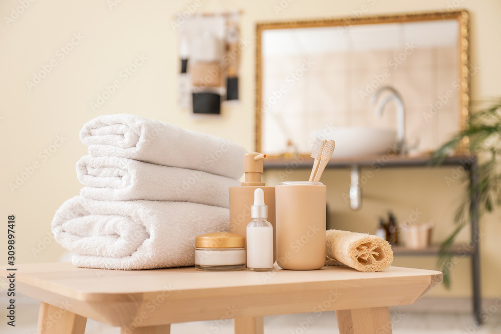 Clean towels with cosmetics and supplies on table in bathroom Clean towels with cosmetics and supplies on table in bathroom