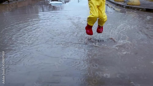 Little girl in a waterproof suit jumping in a puddle. photo