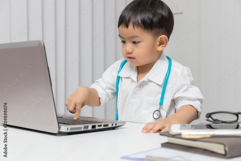 Young asian boy playing doctor and using computer laptop. Young asian boy playing doctor and using computer laptop.