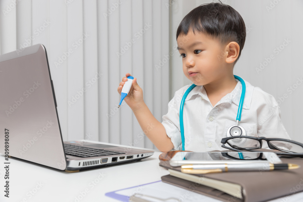 Young asian boy playing doctor and using computer laptop. Young asian boy playing doctor and using computer laptop.