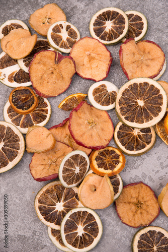 Slices of dry lemon, oranges and apples on a grey structured background