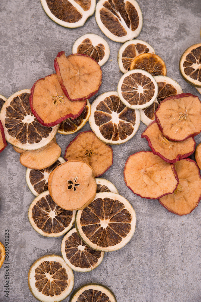 Slices of dry lemon, oranges and apples on a grey structured background Slices of dry lemon, oranges and apples on a grey structured background