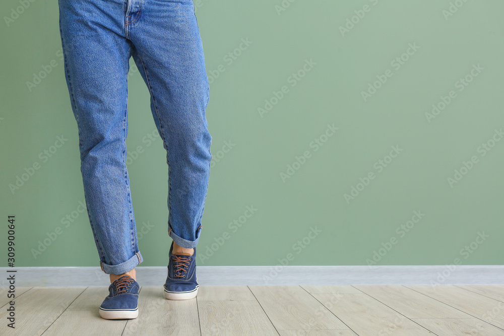 Young man in stylish shoes near color wall
