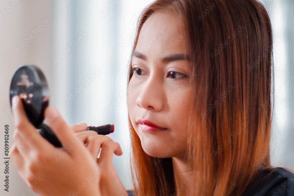 A beautiful young Asian woman wear lipstick on her lip for doing a make up tutorial. A beautiful young Asian woman wear lipstick on her lip for doing a make up tutorial.