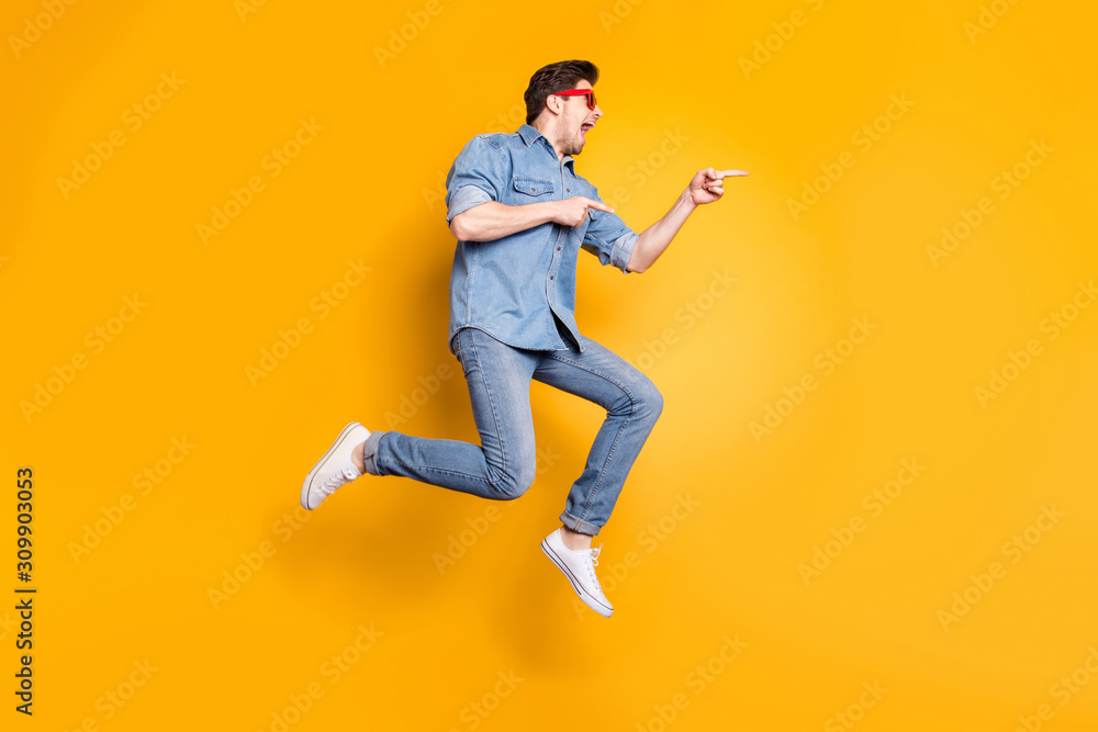 Full length body size view of nice attractive funky crazy cheerful cheery guy jumping pointing aside advert hot tour trip isolated over bright vivid shine vibrant yellow color background