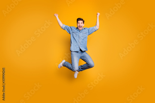 Full length body size photo of brown haired crazy excited rejoicing man jumping up screaming isolated over yellow vivid color background