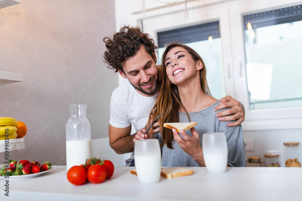 Romantic young couple cooking together in the kitchen,having a great time together. Man and woman laughing and drinking milk in the morning with breakfast