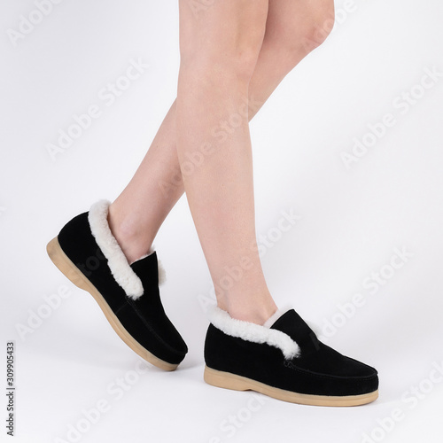 beautiful female warm winter shoes with fur trim on legs of a model on a white background