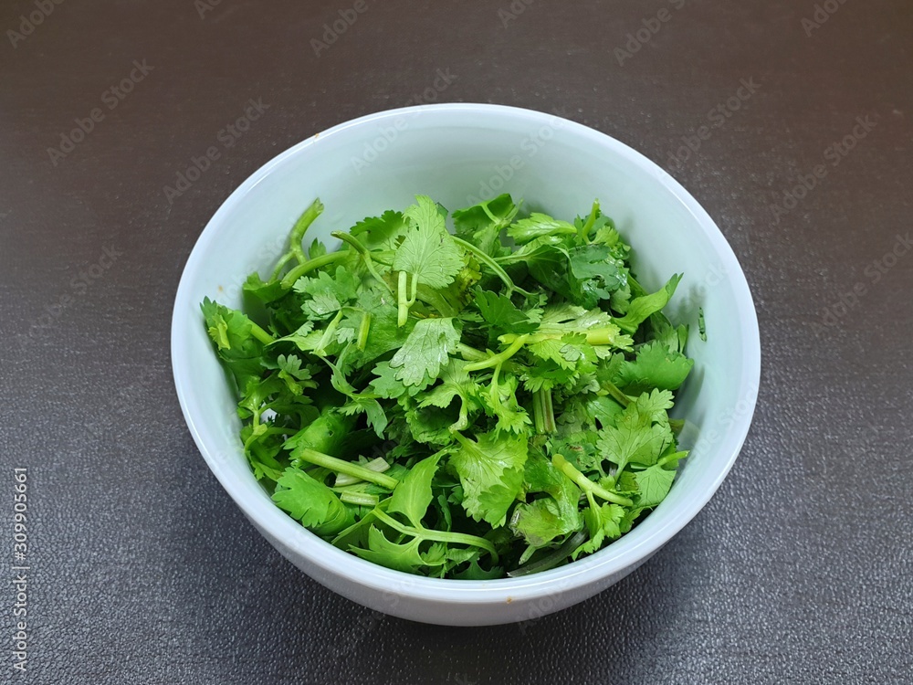 Top view of fresh coriander leaf in white bowl isolated on wooden background for sale in the supermarket, for making cooking, healthy food concept Top view of fresh coriander leaf in white bowl isolated on wooden background for sale in the supermarket, for making cooking, healthy food concept