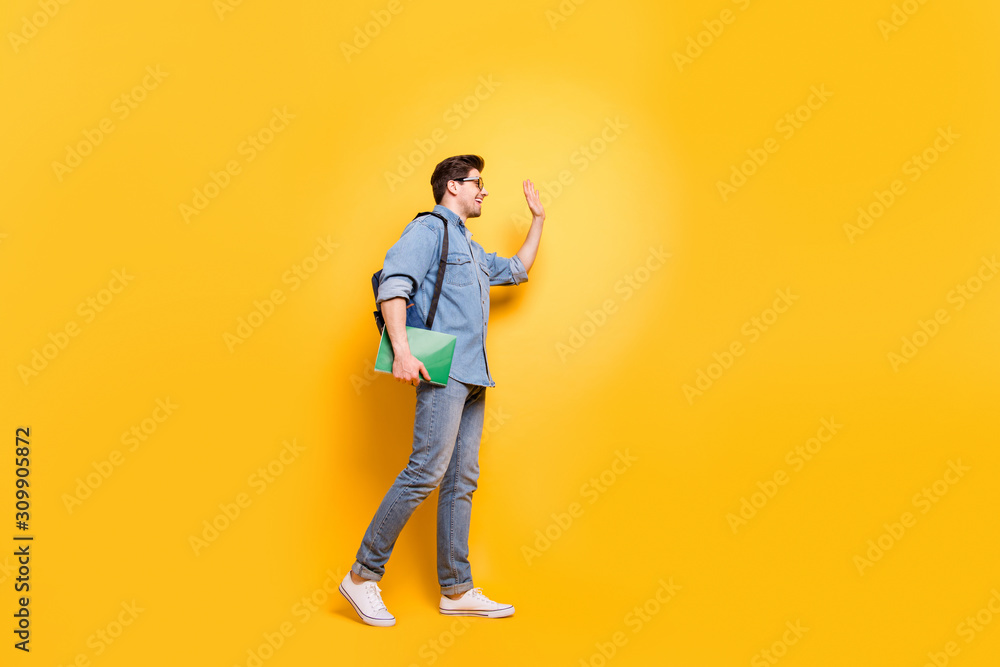 Full length body size profile side view of his he nice attractive cheerful cheery friendly guy walking waving meeting buddy isolated over bright vivid shine vibrant yellow color background
