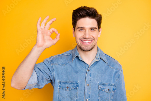 Portrait of positive cheerful guy promoter show okay sign advise promo ads wear casual style clothing isolated over yellow color background photo