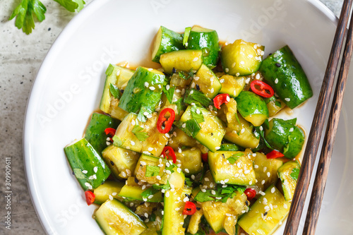 Fotografi Asian smashed cucumber salad with chili and sesame seeds in white bowl, top view