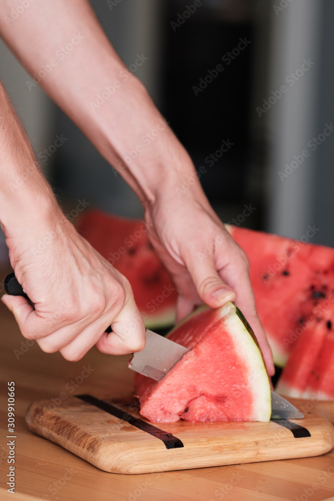 a man slices a watermelon into pieces. Close-up. 