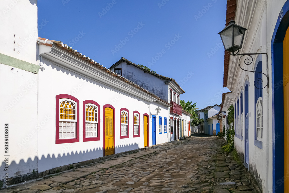 Typical cobblestone street with colonial buildings on a sunny day with shadows in historic town Paraty, Brazil