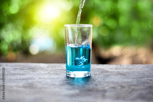 Pour water onto a glass of water with splash on nature background